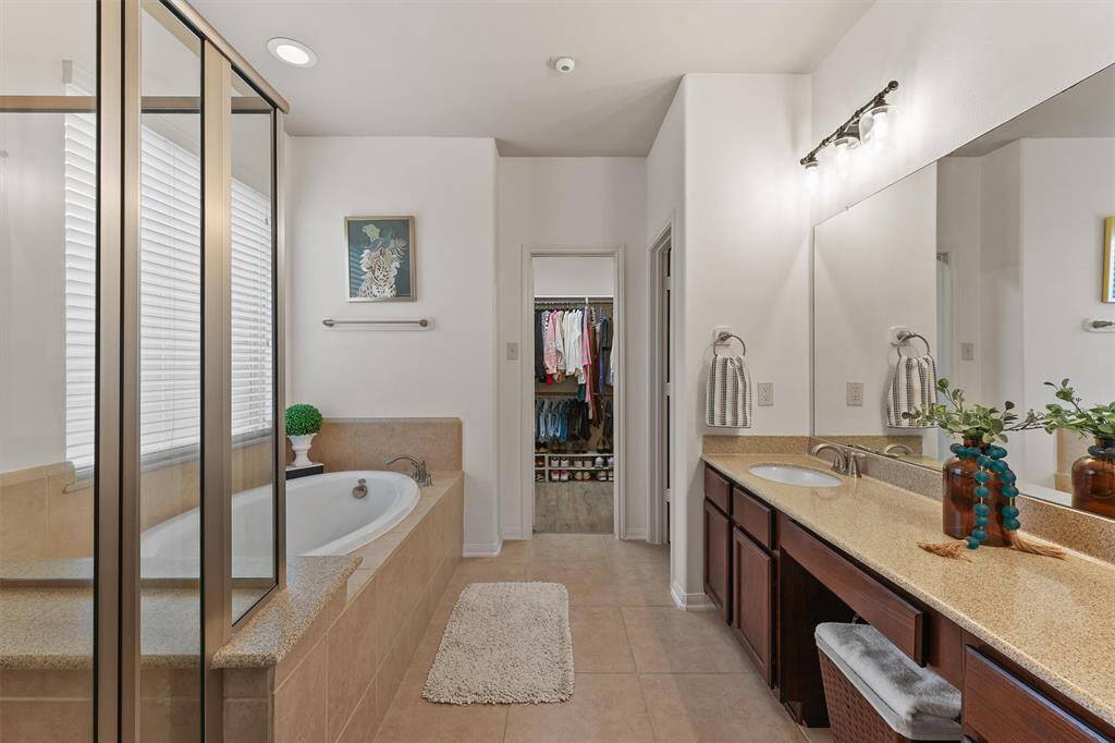 The en-suite bathroom offers a luxurious experience with dual sinks and a spacious vanity, perfect for getting ready in the morning. A relaxing soaking tub invites you to unwind, while the separate glass shower provides a spa-like retreat.