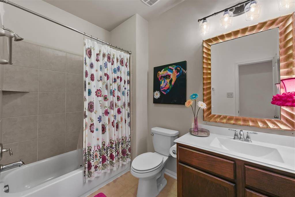 The secondary bathroom features a tub/shower combo, offering both convenience and style. The sleek white countertop and tile flooring provide a versatile backdrop, complementing any décor and adding a fresh, clean look to the space.