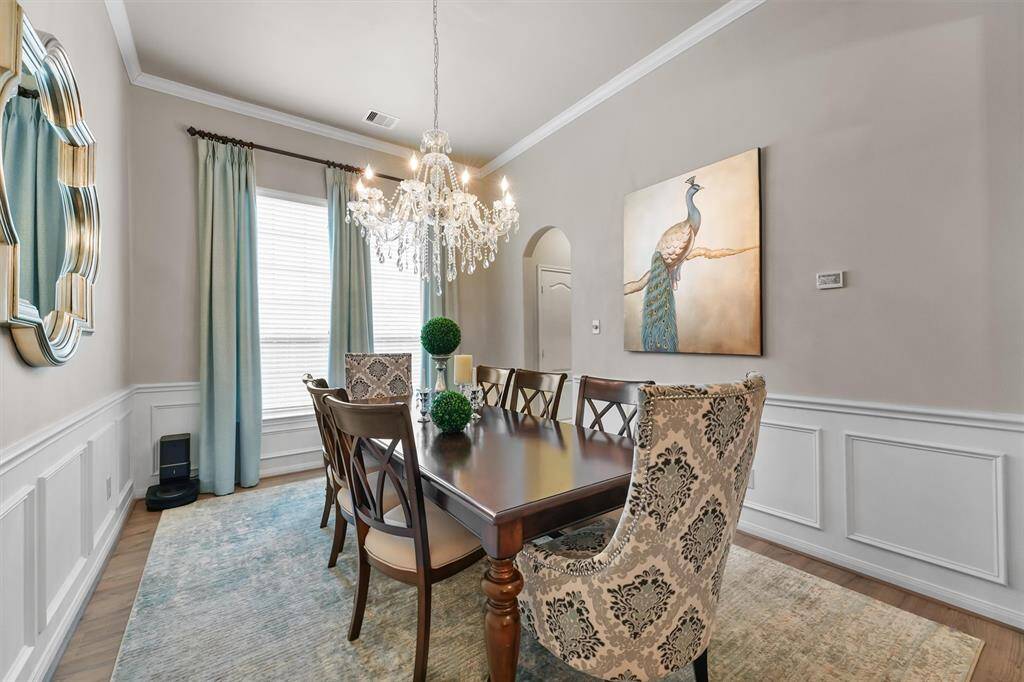 The formal dining room is a sophisticated space, featuring elegant crown molding, detailed wainscoting and a modern light fixture. The chandelier seen here will be replaced with a modern fixture. Image available in the attachments.