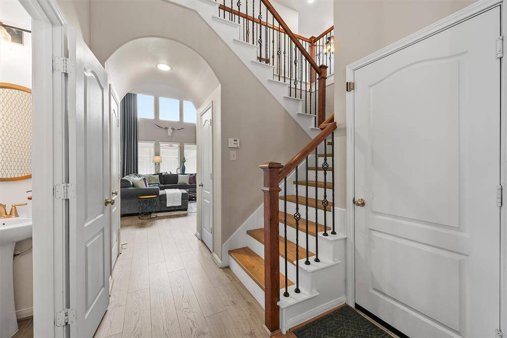 The stunning wood staircase, complemented by elegant wrought iron spindles, gracefully leads you upstairs, adding a touch of timeless charm and sophistication to the home’s interior.