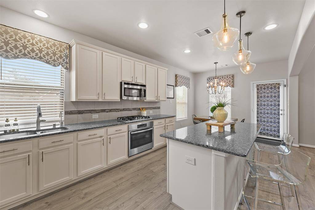The kitchen is bright and airy, with an abundance of windows that fill the space with natural light. It offers plenty of cabinetry for storage, ensuring you have all the room you need for organization and functionality while maintaining an open, spacious feel.