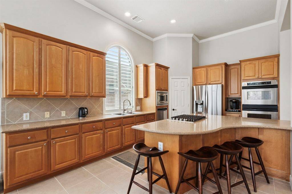 A chef's kitchen with stainless appliances, gas stove, lots of counter space, cabinet storage & a large island with seating.