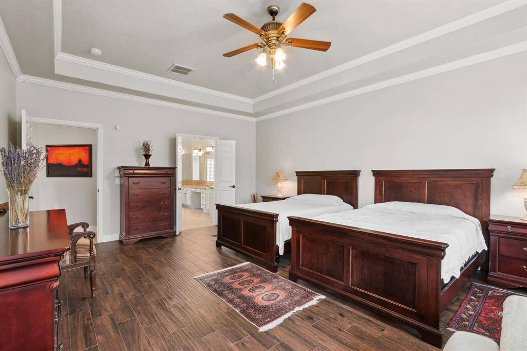 Wood tile plank flooring adds warmth to a such a large room.  Double French doors lead to the huge primary spa bath.