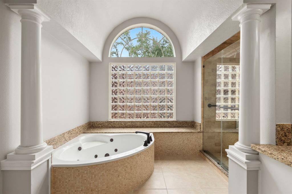 The added luxury of a Romanesque alcove offers a garden tub & seating area.  Natural light filters in from the large window & arched transom.