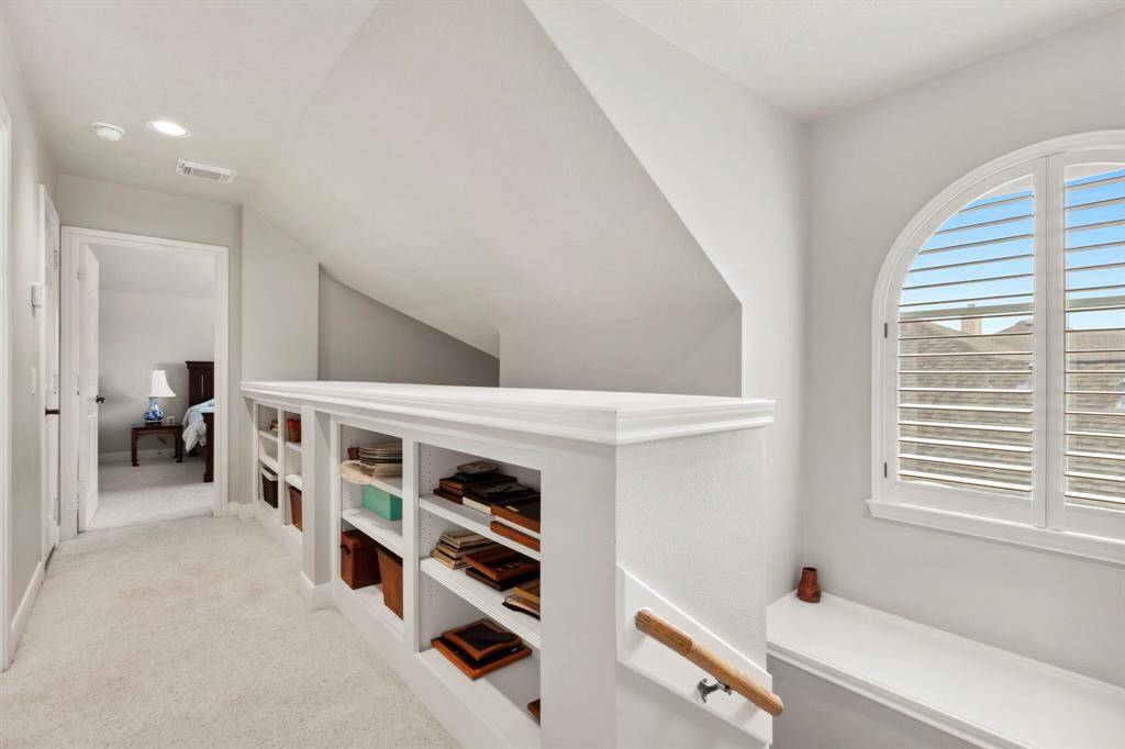 Upstairs in the main house you will find a second bedroom & full bathroom.  The hallway area features built-in shelving for storage, a beautiful arched picture window & walk-in attic access.