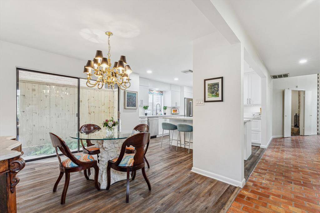 Perfect for casual dining, the bright and inviting breakfast room conveniently connects to the kitchen, featuring wood-look flooring, a statement chandelier, and sliding glass doors that bring in natural light.