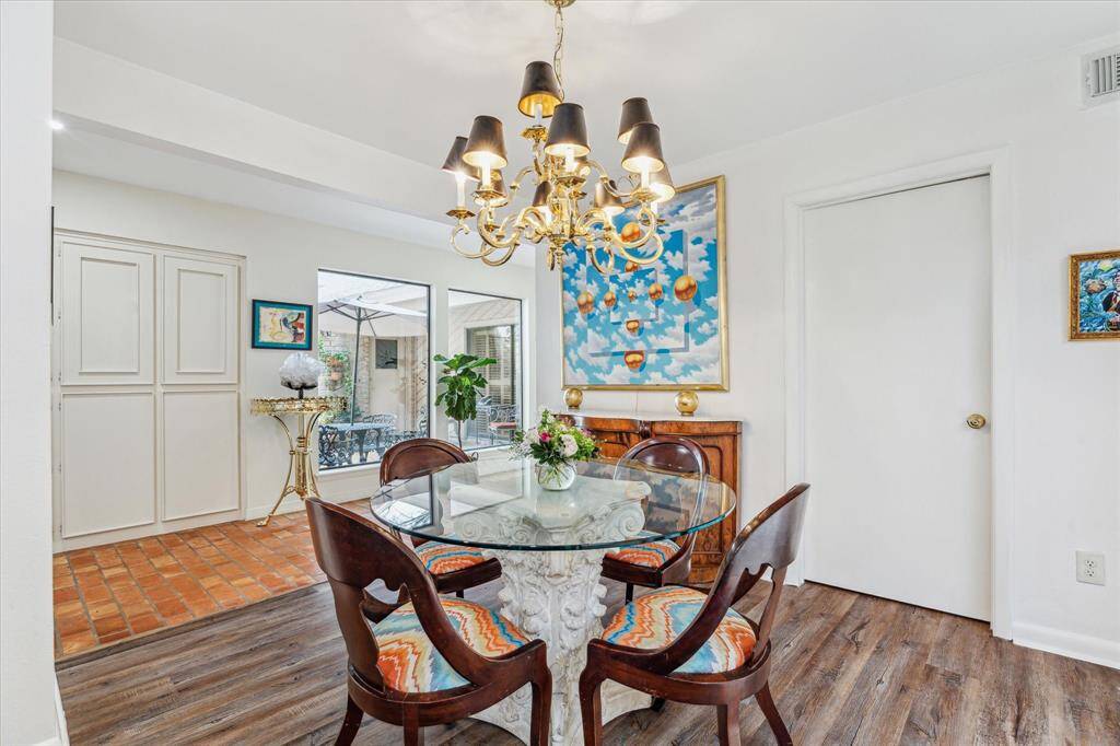 This alternate view of the breakfast room highlights a wall of built-in cabinetry for ample storage, large picture windows with views of the central courtyard, and a conveniently located door to the right, leading to the spacious walk-in utility room, which comfortably accommodates a full-size, side-by-side washer and dryer.