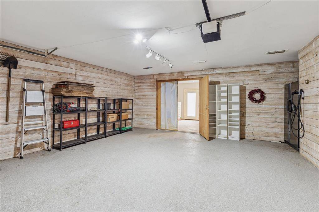 Wood-paneled 2-car detached garage with epoxy flooring is air-conditioned and provides a 220V EV charger. Double doors open to an adjoining air-conditioned workshop/studio with a sink