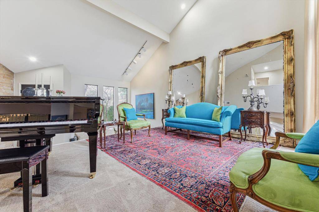 The raised living room (or dining room) features soaring cathedral ceilings with recessed lighting, and floor-to-ceiling windows that flood the home with natural light and overlook a central courtyard.