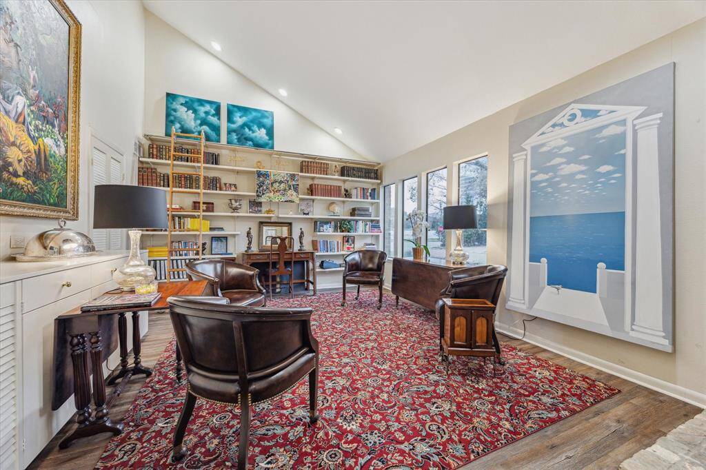 The library boasts a dramatic vaulted ceiling with recessed lighting, a wall of windows that overlook the front lawn, and a cozy wood-burning fireplace.