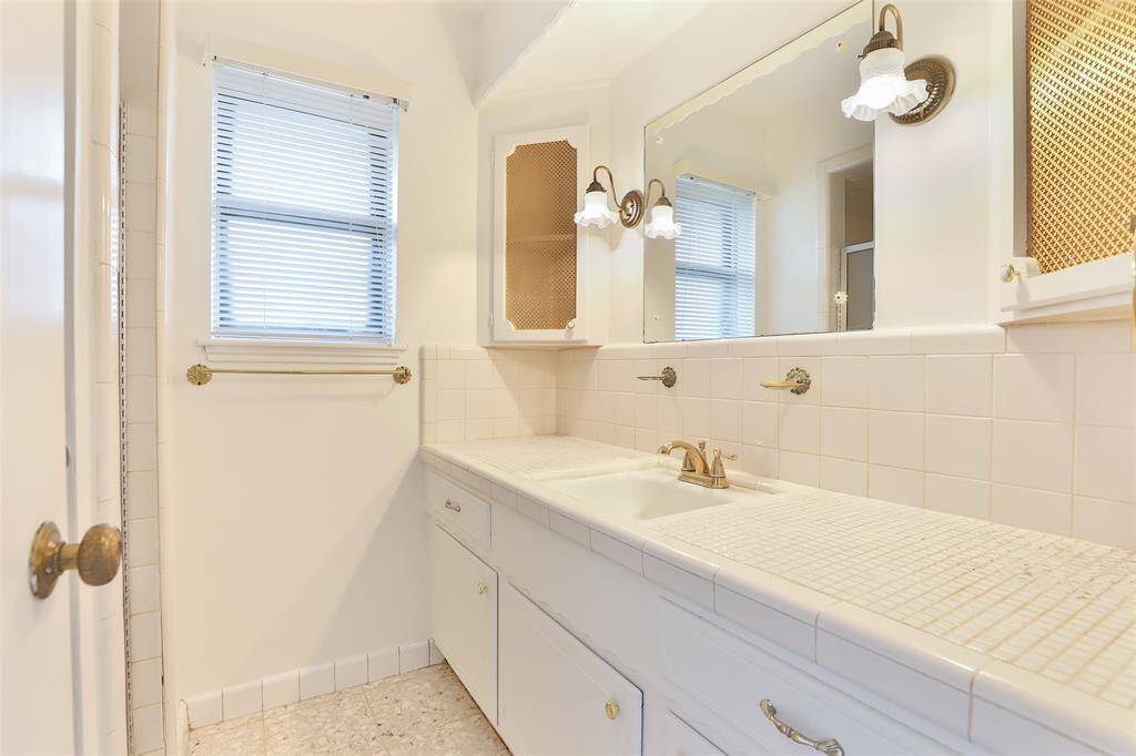 Your primary bath with original tile, corner storage cabinets and stand alone shower.