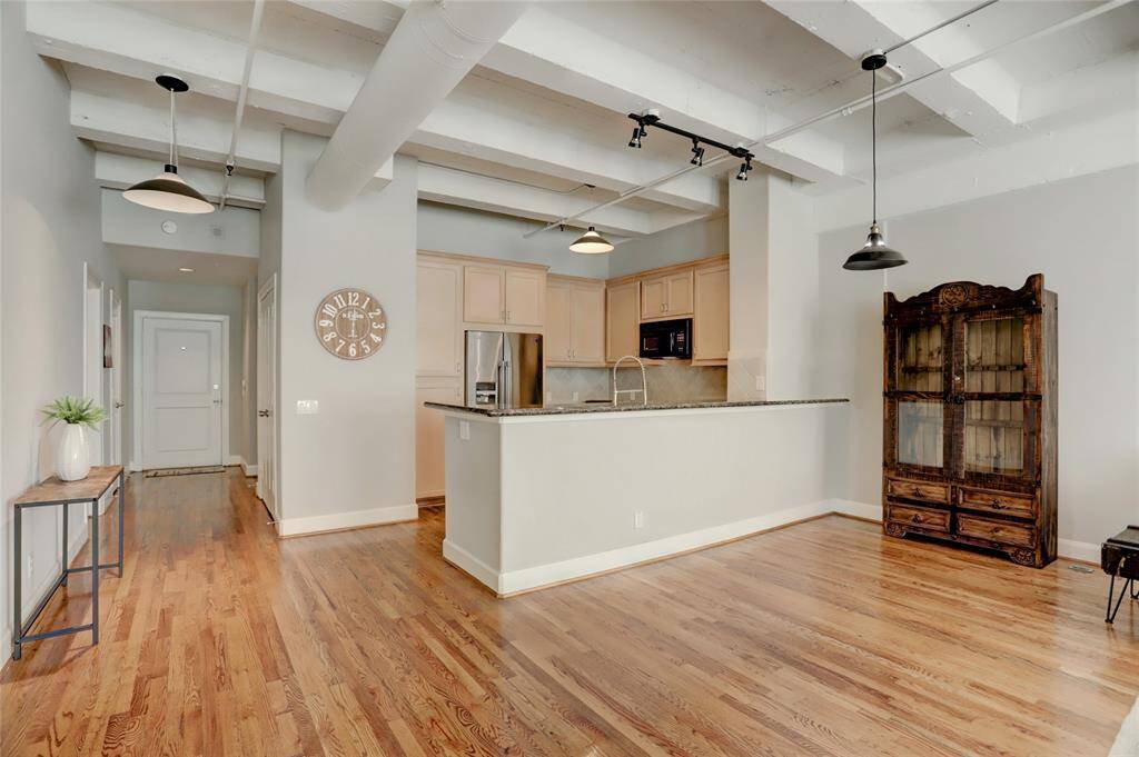 A wider view from the living space showcases the kitchen, where the breakfast bar doubles as a sitting area or gathering spot for entertaining. The open layout of this unit enhances the sense of space, making it perfect for both casual and social gatherings.