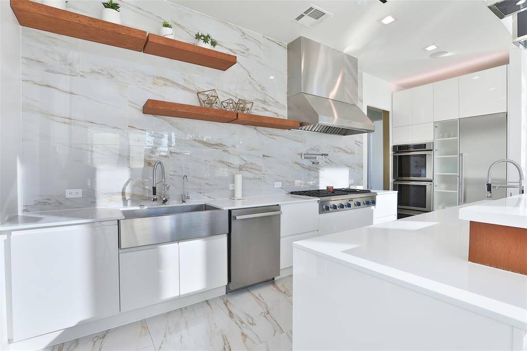 A chef's delight awaits with Thermador appliances including a 6 burner gas cooktop and griddle, dual ovens with warming drawer, built-in fridge, vegetable prep sink, pot filler, & custom soft close cabinetry.