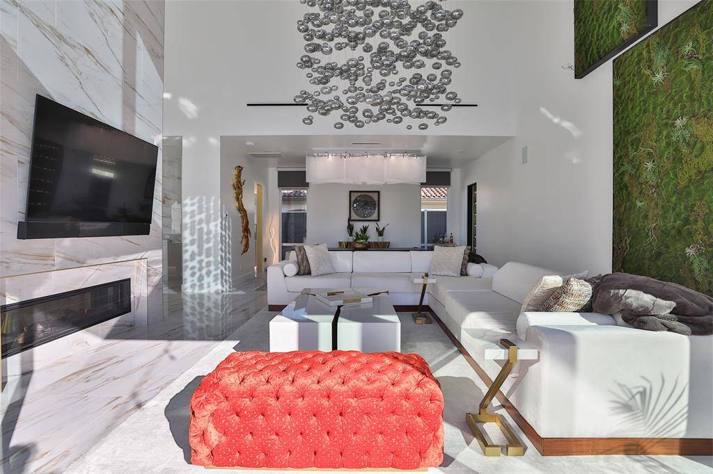 The room boasts an open floor plan, allowing for seamless transition between the living, dining, and kitchen areas. The sleek white lines are complemented by the green moss wall that creates a unique focal point.