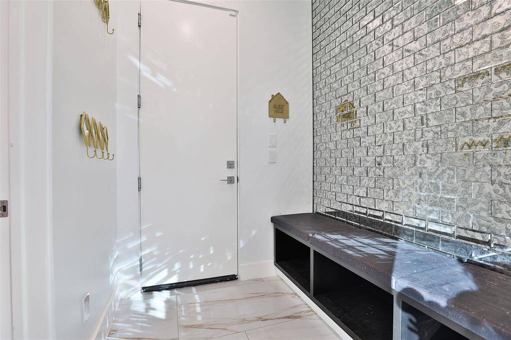 The drop zone/mud room features stunning glass subway tiles and padded seating bench for shoes and kid backpacks. Not shown to the left is the oversize laundry room. A 2nd laundry room is situated upstairs for the kiddos to keep clutter at bay.