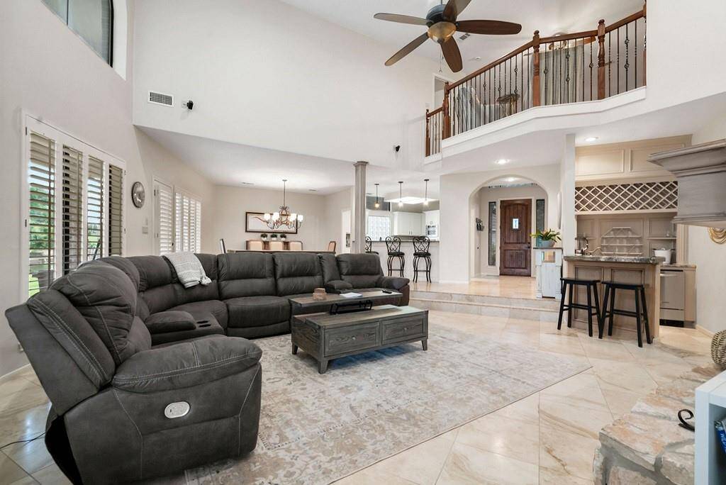 Spacious and inviting living area with high ceilings, elegant staircase, and abundant natural light. Perfect for relaxation and entertaining.