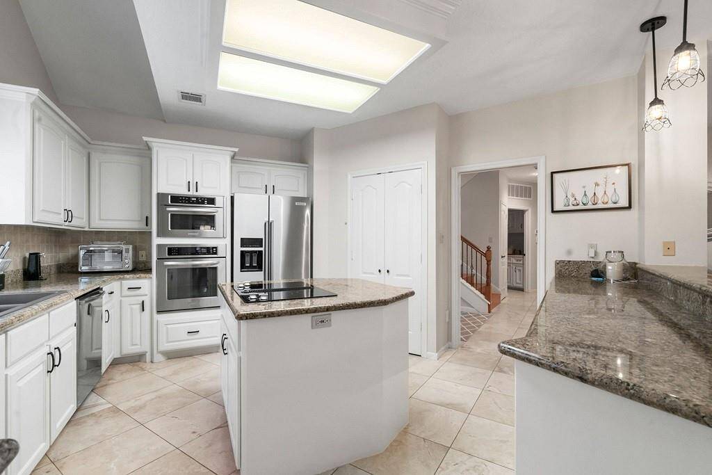 Spacious kitchen featuring sleek granite countertops, modern stainless steel appliances, and ample storage in elegant white cabinetry. Ideal for culinary enthusiasts and hosting gatherings.