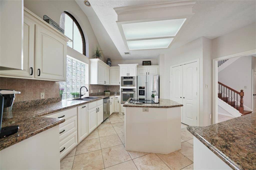 Spacious kitchen with sleek granite countertops, abundant cabinetry, and modern stainless steel appliances. Bright and inviting with large windows and a central island perfect for cooking and entertaining.