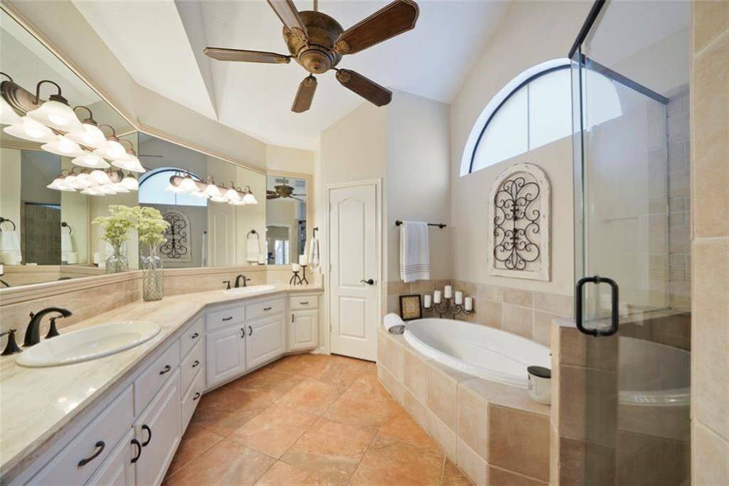 Luxurious primary bath featuring dual vanities, a spacious soaking tub, and elegant tile accents.
