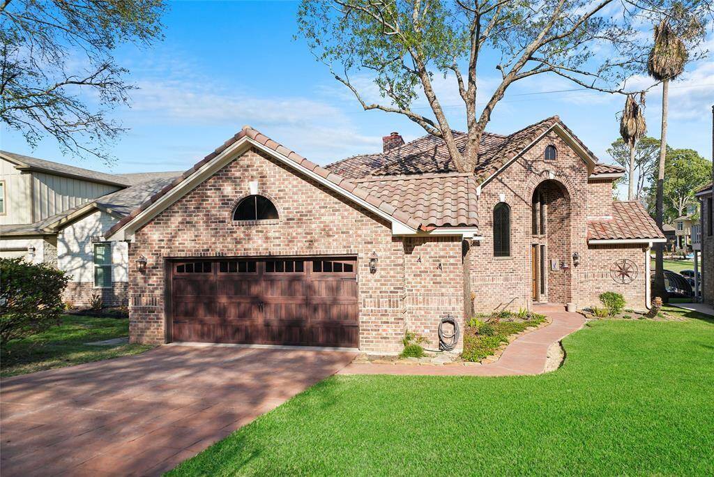Charming brick home with elegant arched windows, a welcoming pathway, and a spacious two-car garage. Perfect blend of style and functionality.