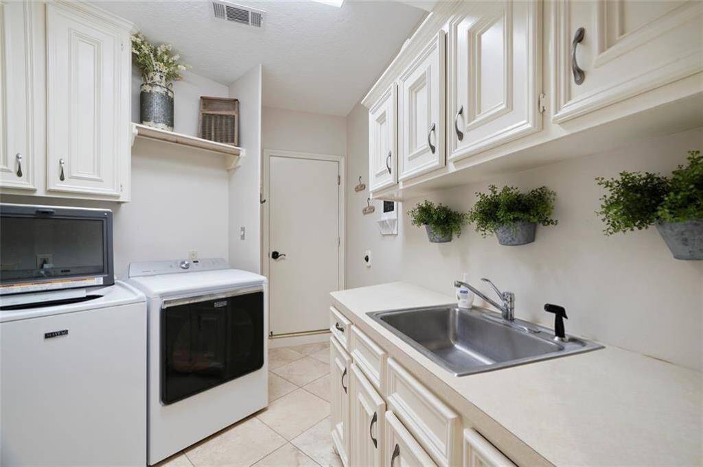 Streamlined utility room featuring modern appliances, ample storage, and a convenient sink area for all your laundry needs.