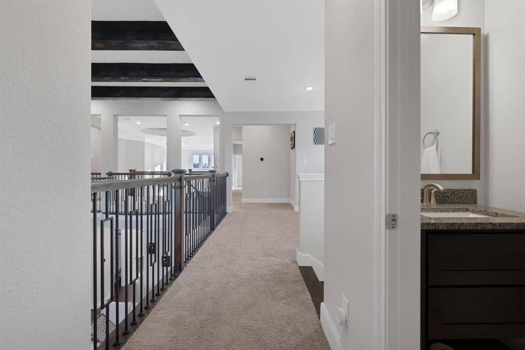 The upper-level hallway with carpeted flooring, featuring an open railing that overlooks the level below.