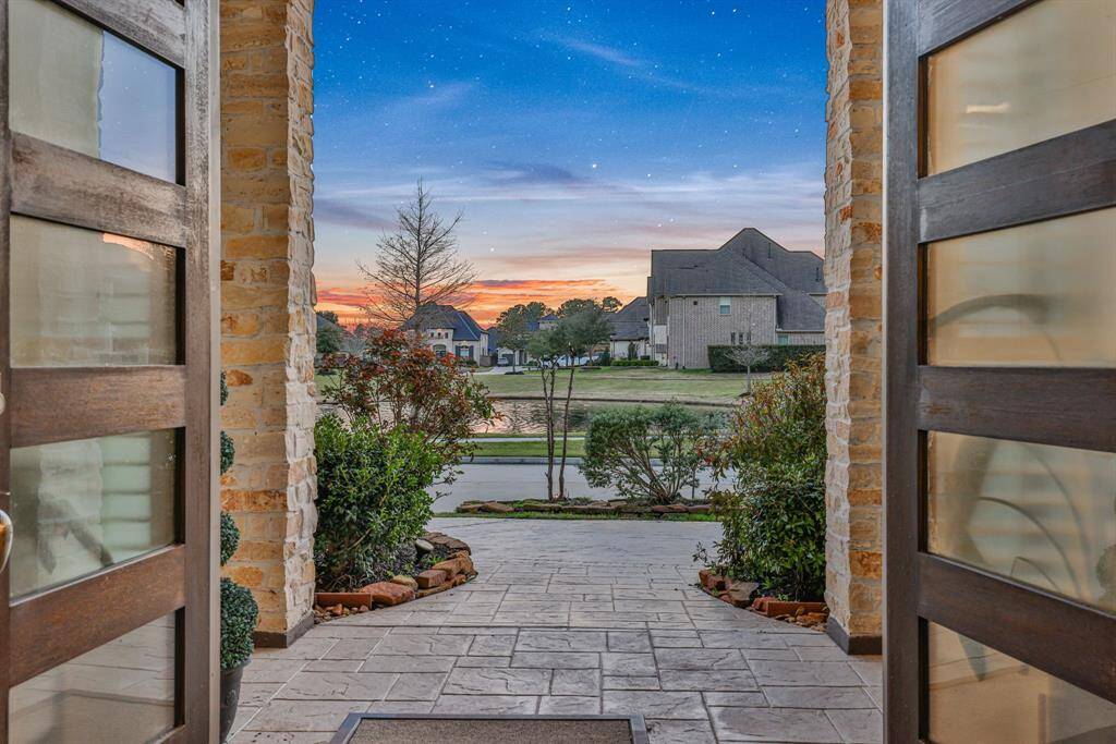 The welcoming front entrance with elegant double doors, leading to a paved walkway surrounded by lush greenery. The view opens up to no front neighbors.