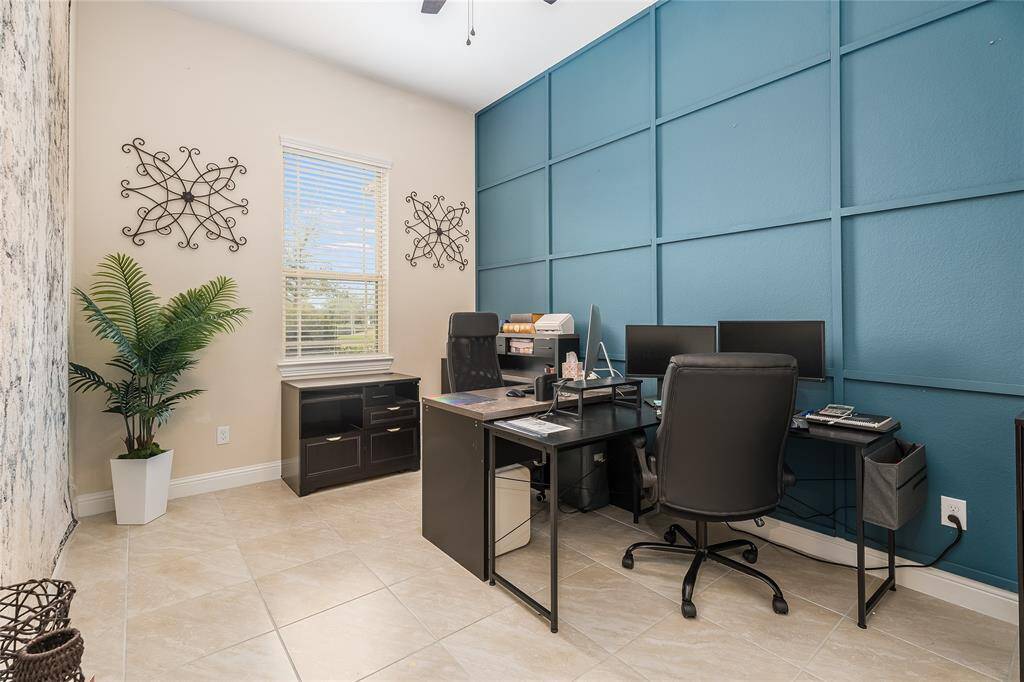Study/office with high ceilings, natural light, and custom wall