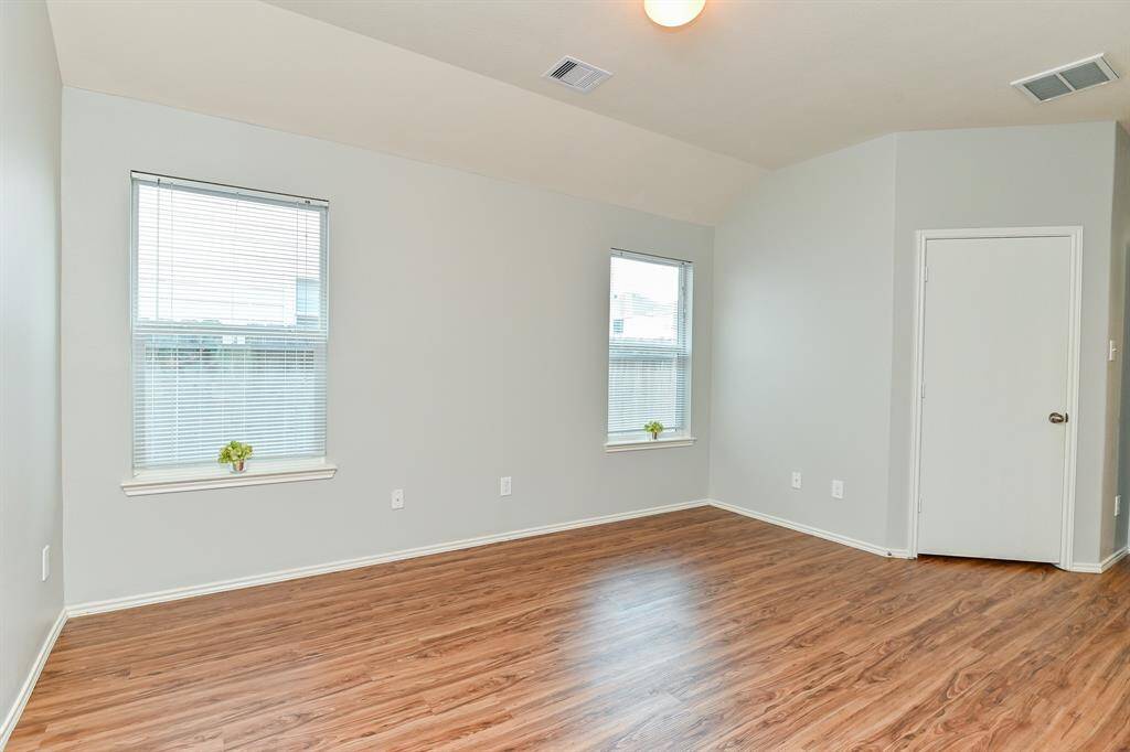 Spacious primary bedroom with high ceilings and recent laminate floors.