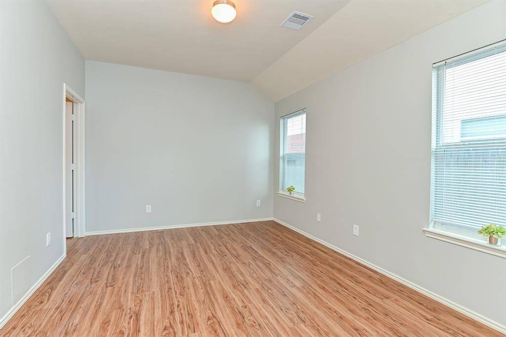 Spacious primary bedroom in excellent condition, featuring elegant flooring and direct access to the primary bathroom.