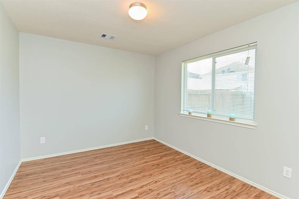 Spacious guest bedroom with high ceilings and sleek flooring.