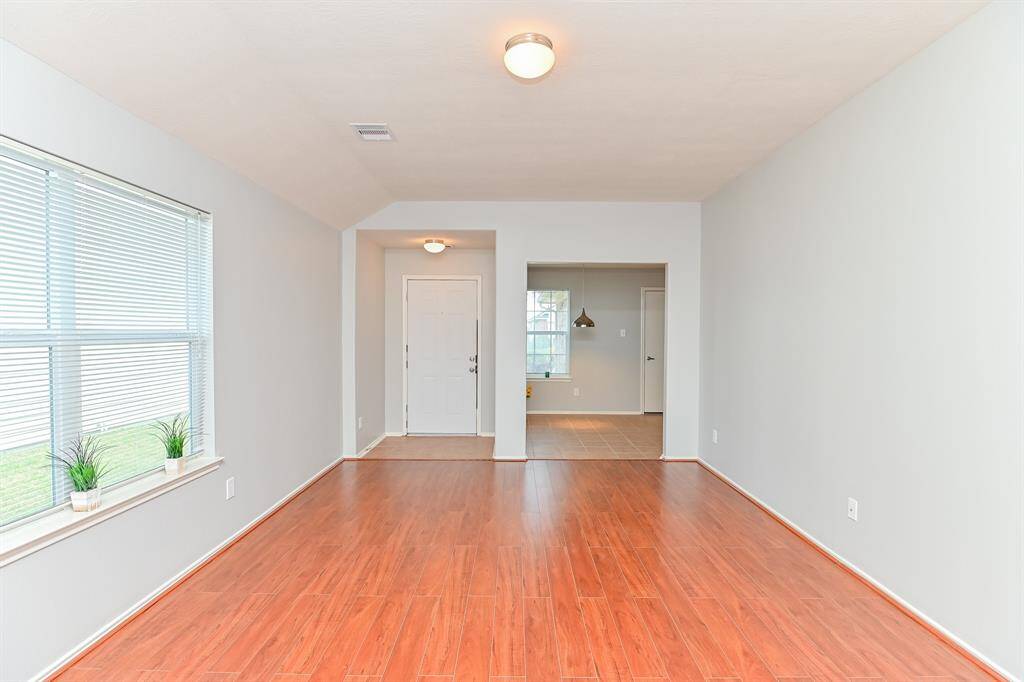 Here's a concise and compelling description for a home buyer:"Inviting living room with a view of the front door and breakfast area, perfect for seamless living.