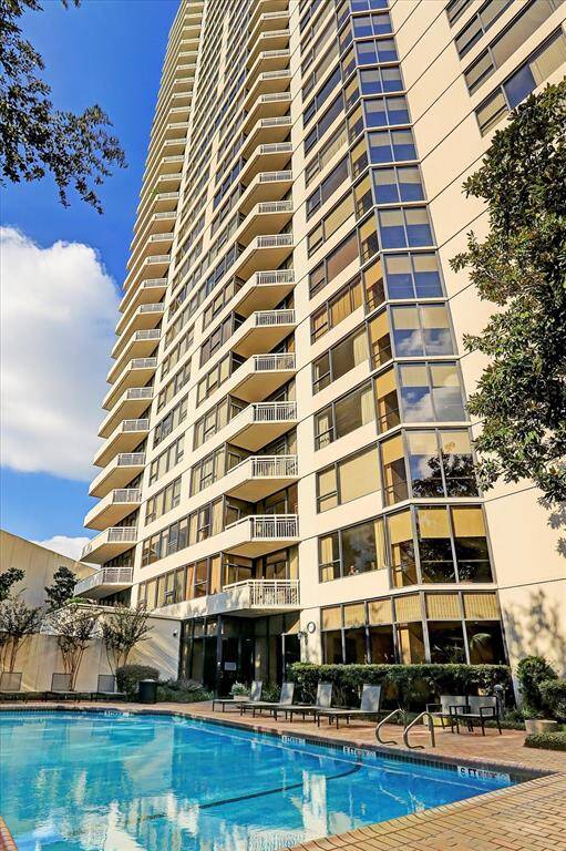 This photo showcases a modern high-rise building with multiple balconies and large windows, offering ample natural light. In the foreground, there's a spacious pool area surrounded by seating, perfect for relaxation and recreation. The building's sleek design and amenities make it an attractive option for potential home buyers.