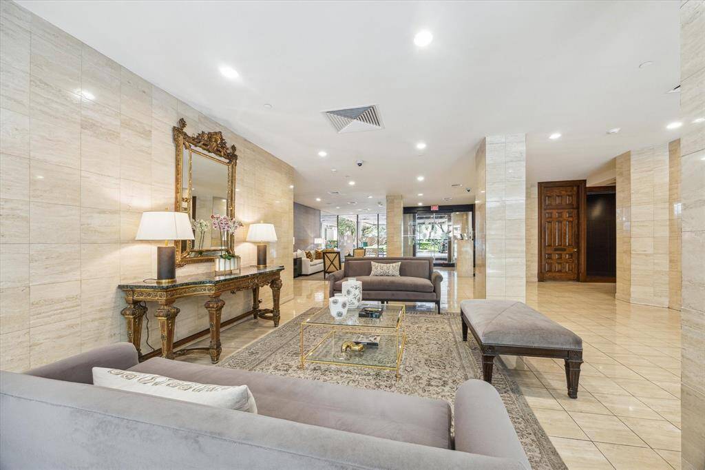 This elegant lobby features luxurious furnishings, including plush sofas and ornate tables. The space is bright and inviting, with polished tile floors, a decorative mirror, and ample lighting, offering a welcoming atmosphere for residents and guests.