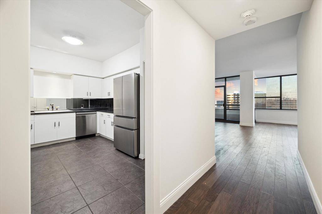 Take a peek into the remodeled kitchen with new, sleek stainless steel appliances, white cabinetry, and dark countertops. Large pantry to the right of the refrigerator.