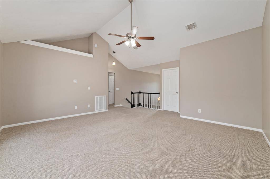 The upstairs landing opens into a large great room with vaulted ceilings, a wall of windows for natural light, and a fan for energy efficiency.