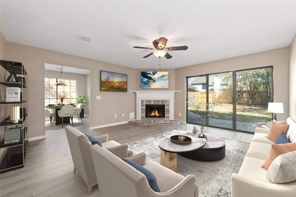 The spacious living room is the heart of the home featuring a brick surround fireplace, large windows, and a sliding glass door offering direct access into the backyard. Virtually staged.