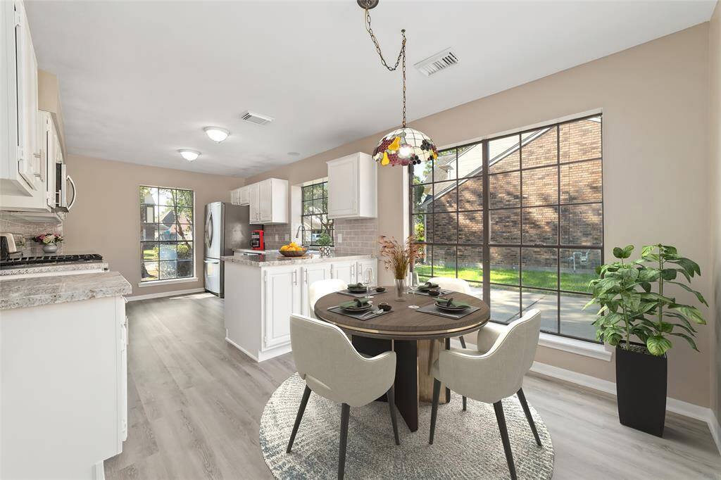 Beautifully renovated chef’s kitchen with granite counter tops, subway tile backsplash, durable luxury vinyl plank flooring, white cabinetry, and modern stainless-steel appliances. Virtually staged.