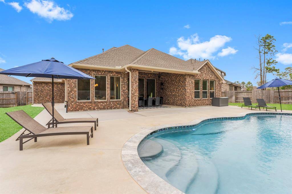 Your private outdoor retreat offers a pristine pool, spacious patio, and shaded lounge areas with umbrellas and chairs, blending comfort and luxury.