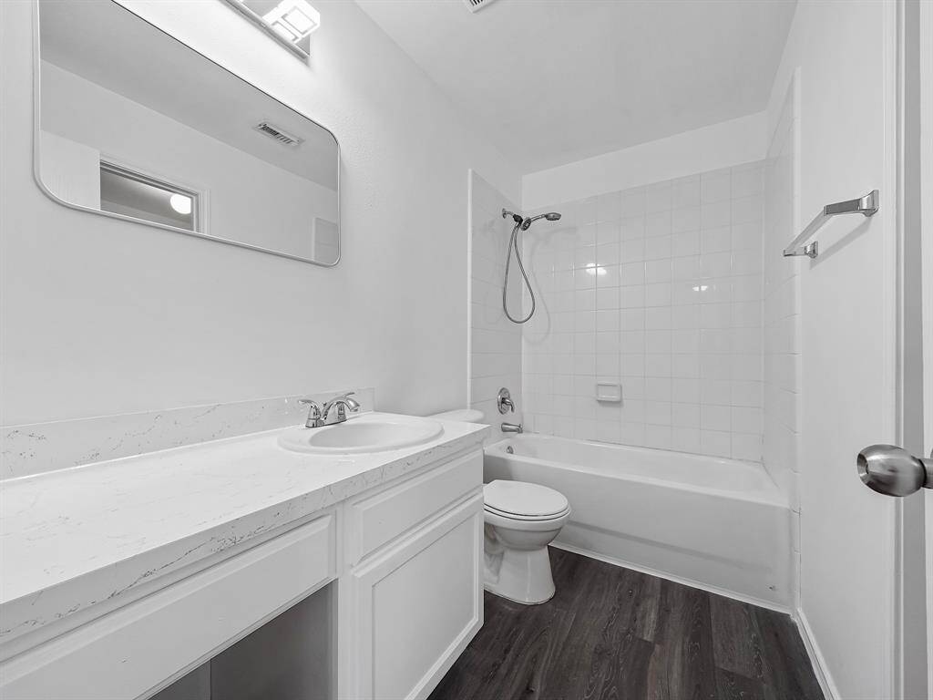 Primary bathrooms offers new white vanity with seating area, new mirror, tub/shower combo and new water-proof laminate flooring.