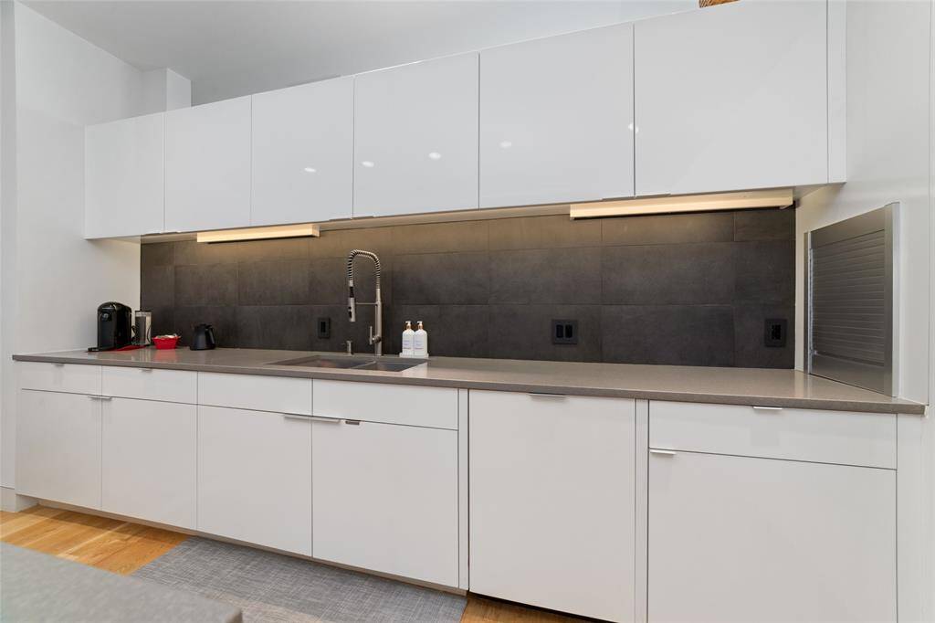 The streamlined Miele kitchen features a 5-burner gas cooktop with a disappearing downdraft, a 36” refrigerator over freezer drawers, a microwave/convection oven, and a quiet dishwasher.