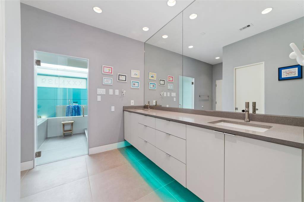 The sleek cantilevered floating designer base cabinets, topped with luxurious Silestone and double sinks, offer a modern aesthetic. Adding to the ambiance, LED lighting beneath the cabinets allow you to customize the color to suit your mood.