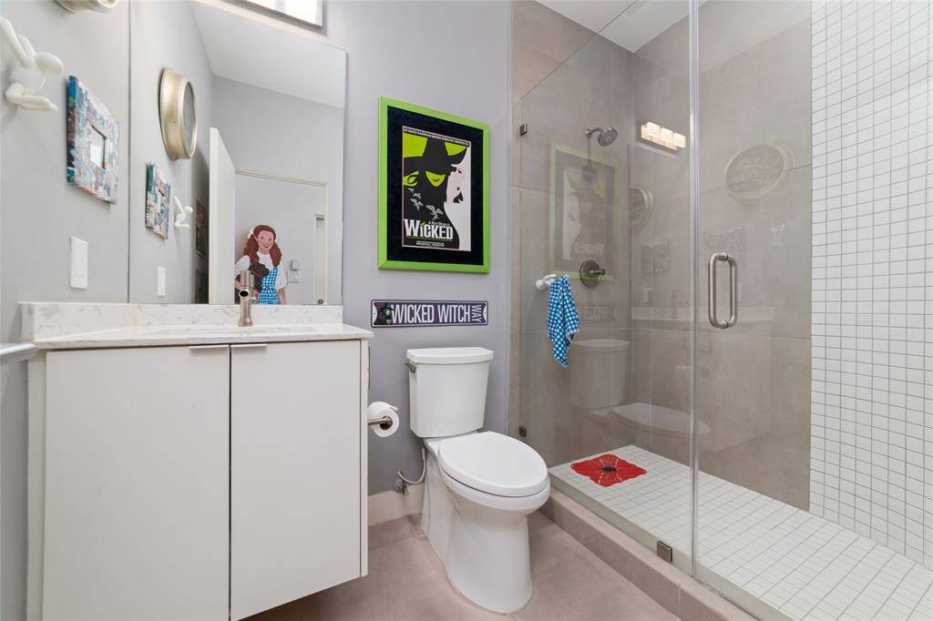 Ground-floor bedroom with a walk-in closet, two walls of built-in shelving, and direct access to a private patio. A full bath is just outside the door for added convenience. This versatile space is perfect for use as a bedroom, home office, or media room.