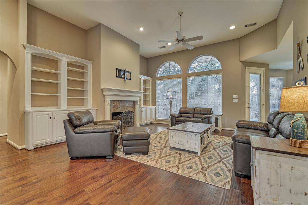 The living room features hard wood flooring, a wall of windows and a ton of natural light.