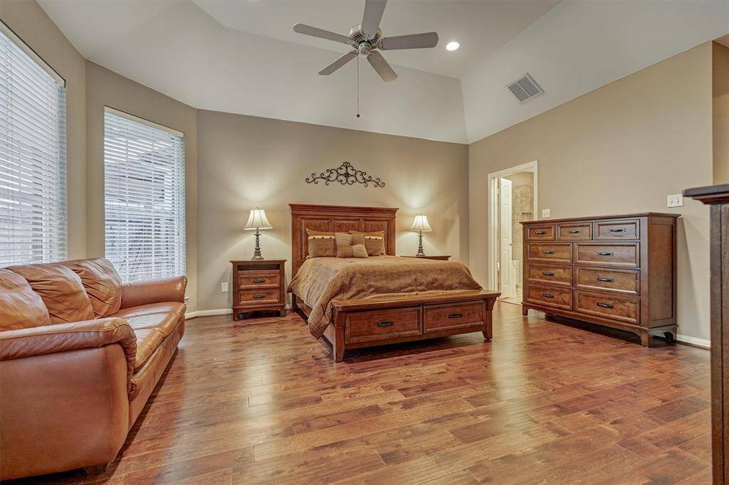 The private primary retreat enjoys rich wood flooring, soaring ceilings and large windows.
