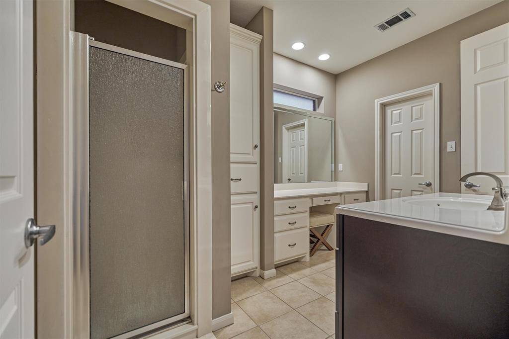 The secondary bathroom has a sink area, an additional vanity area and a walk-in shower.