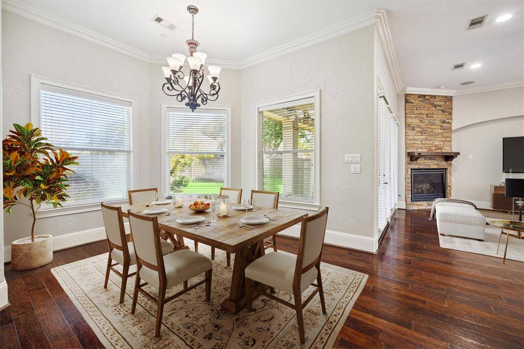 From the breakfast area, enjoy a stunning view that highlights the home's expansive open floor plan and seamless flow between the kitchen, dining, and living areas. Large windows flood the space with natural light while offering picturesque views of the backyard, creating a bright and inviting atmosphere. (Digitally Staged)