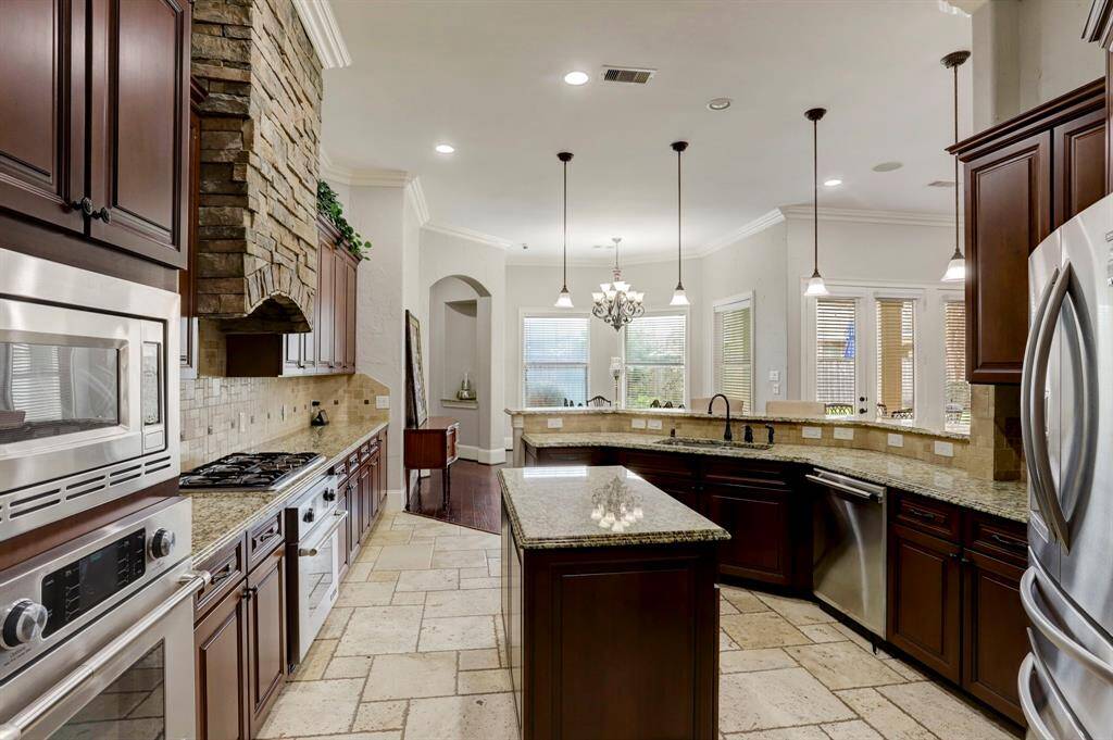 A chef’s dream come true, this stunning kitchen is designed for both everyday living and effortless entertaining. The expansive breakfast bar serves as a perfect gathering spot for conversation or as the ideal space to showcase a party spread for guests to enjoy. Featuring sleek granite countertops, built-in stainless steel appliances, and rich dark cabinetry, this kitchen blends style and functionality seamlessly.