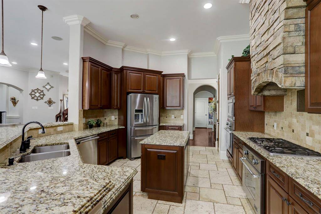 Admire the stunning detail of the granite countertops, featuring a sleek waterfall edge that adds a touch of luxury and sophistication. This elegant design not only enhances the beauty of the kitchen but also serves as a functional focal point.