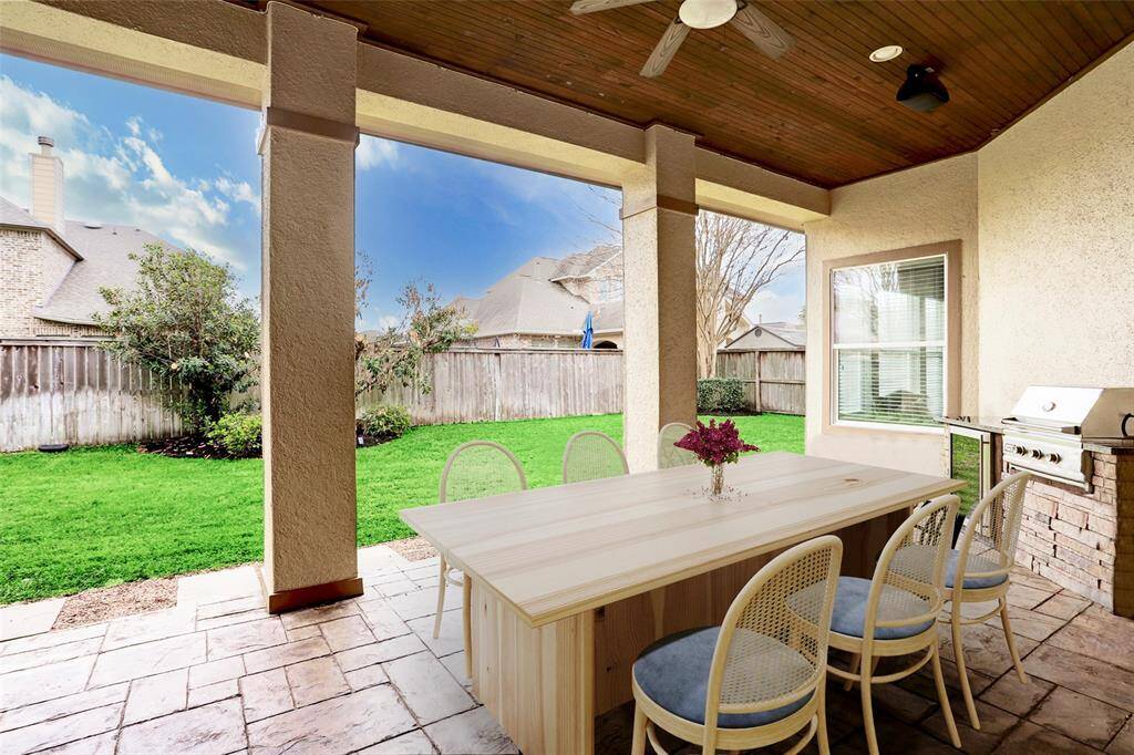 Unwind and entertain in style on this expansive covered outdoor patio, designed for year-round enjoyment. Featuring elegant stone flooring, and a convenient mini fridge, this space is perfect for hosting gatherings or simply relaxing in the fresh air. (Digitally Staged)